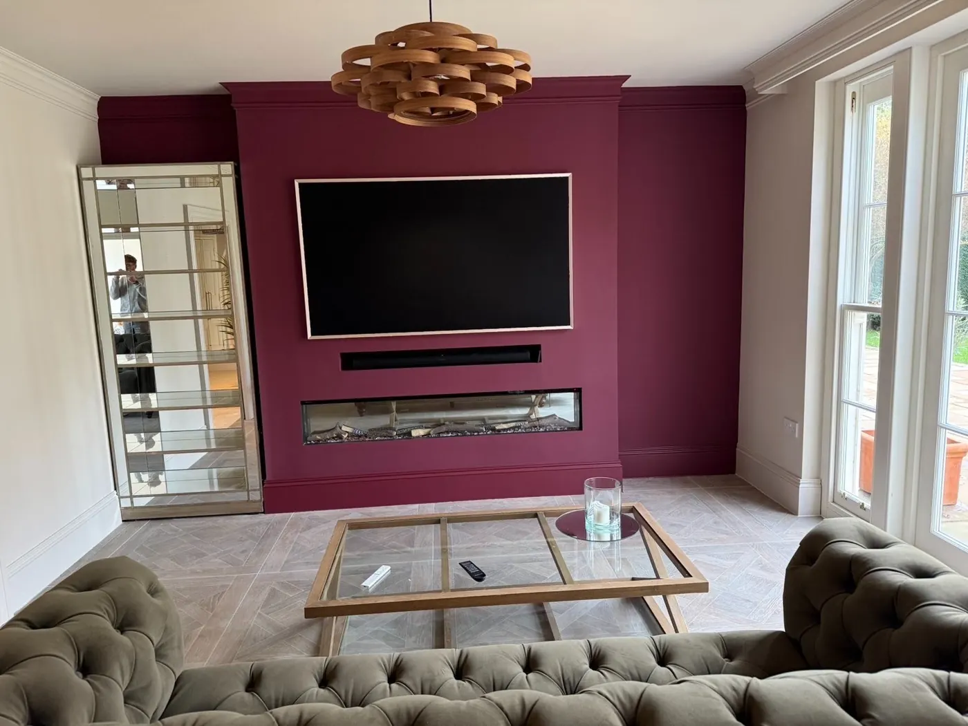 Living room with a deep burgundy painted feature wall and crisp white trim, finished by Martin And Co. Decorating