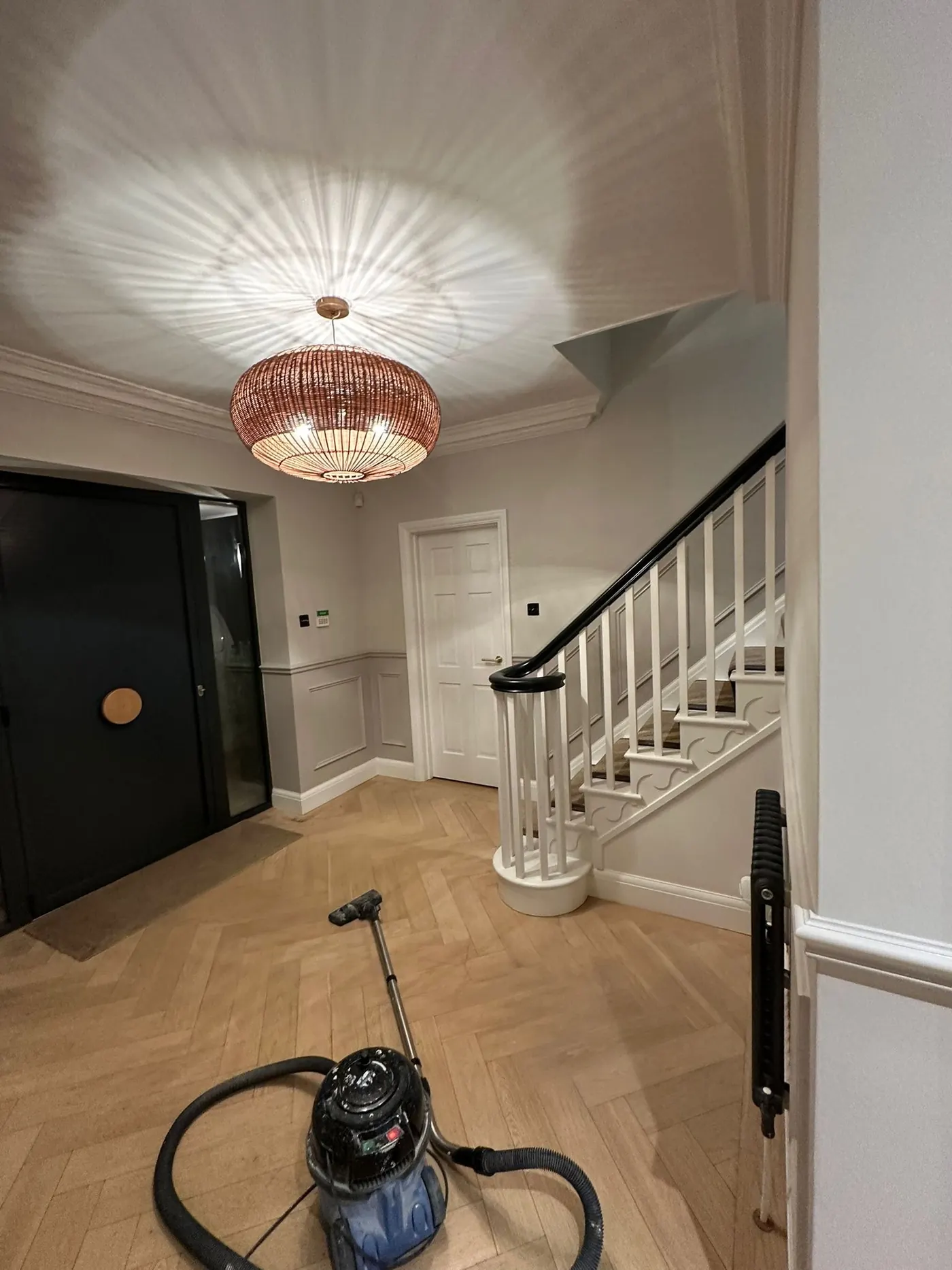 Freshly decorated entrance hallway and staircase with herringbone oak flooring, painted by Martin And Co. Decorating in Surrey