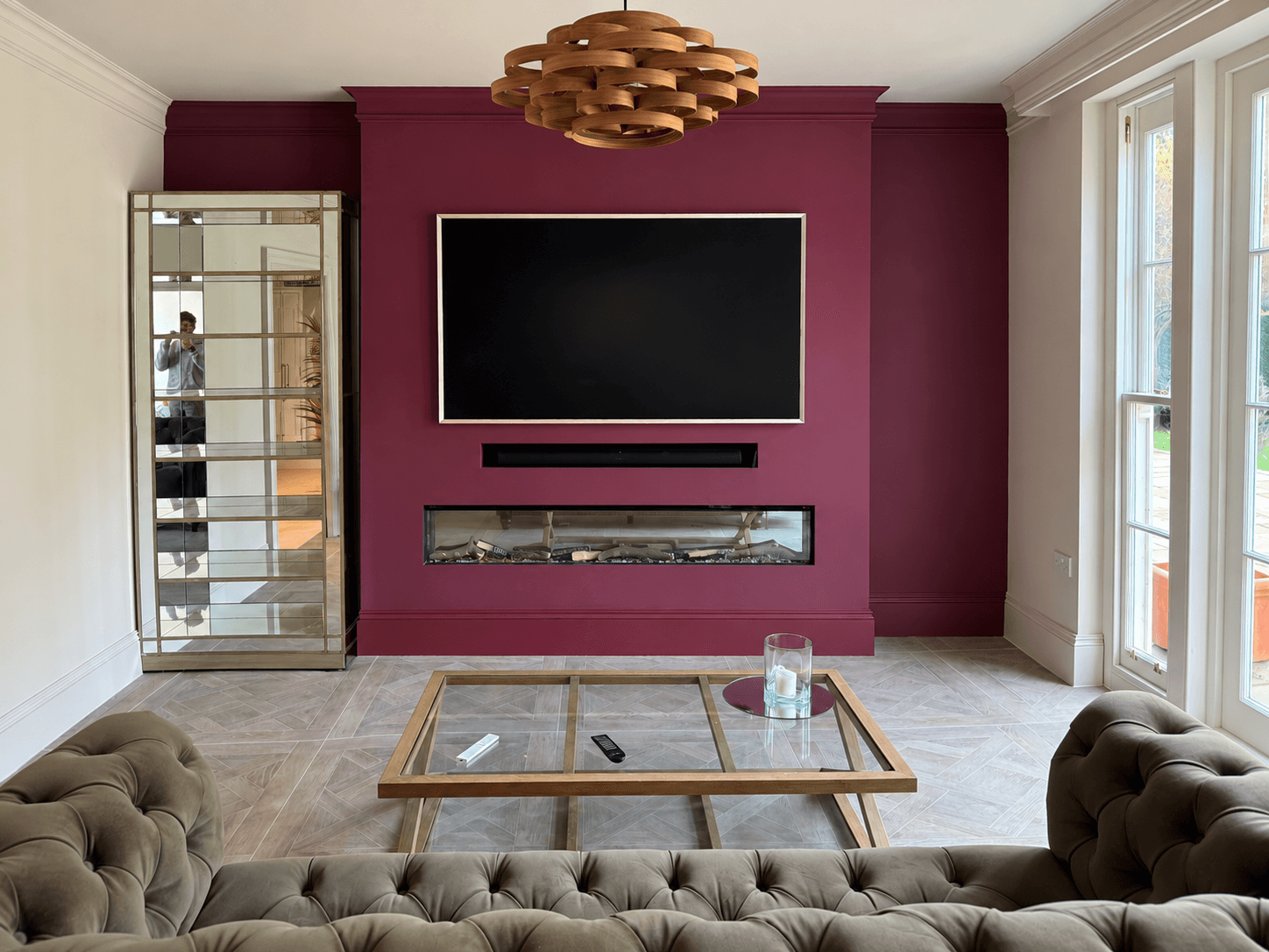 Deep burgundy TV and fireplace feature wall in a Guildford living room, finished by Martin And Co. Decorating