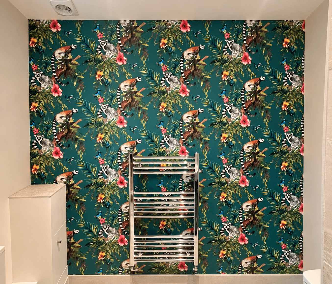 Wallpapering service: teal tropical wallpaper with lemurs, hibiscus flowers and palm leaves installed on a bathroom feature wall by Martin And Co. Decorating